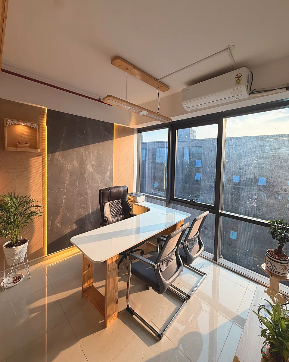 The Gold Squirrel Studio cabin: a white desk against a grey stone wall, beside floor-to-ceiling windows